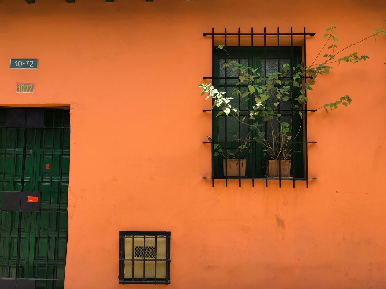 Fachada colonial ecuatoriana con ventanas enrejadas y plantas