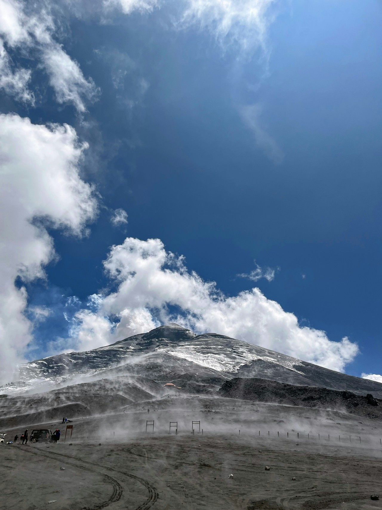Volcán Cotopaxi con ceniza y nieve bajo cielo azul