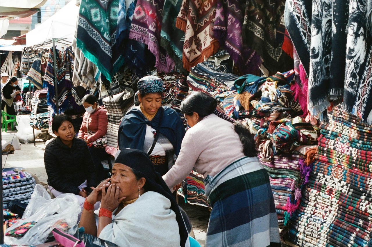 Mercado indígena de Otavalo con comerciantes y textiles artesanales