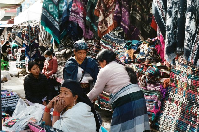 Mercado indígena de Otavalo con comerciantes y textiles artesanales