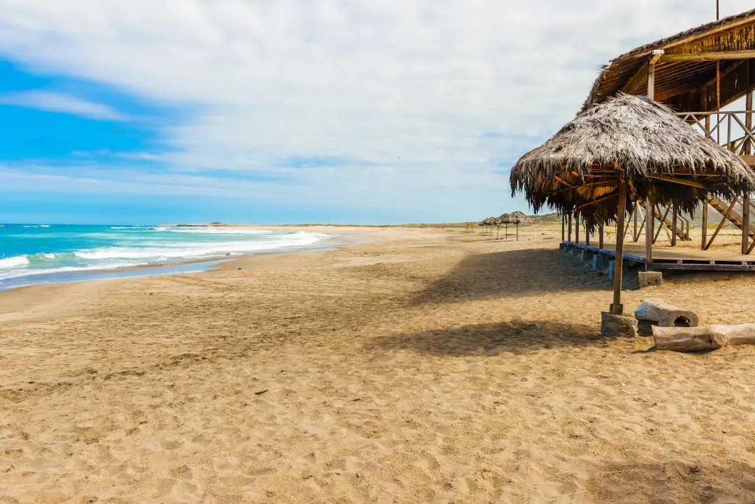 Playa virgen de la costa ecuatoriana con infraestructura turística tradicional