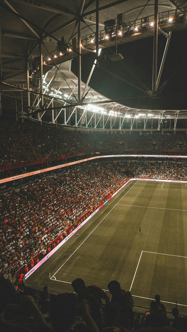 Estadio de fútbol lleno durante partido nocturno