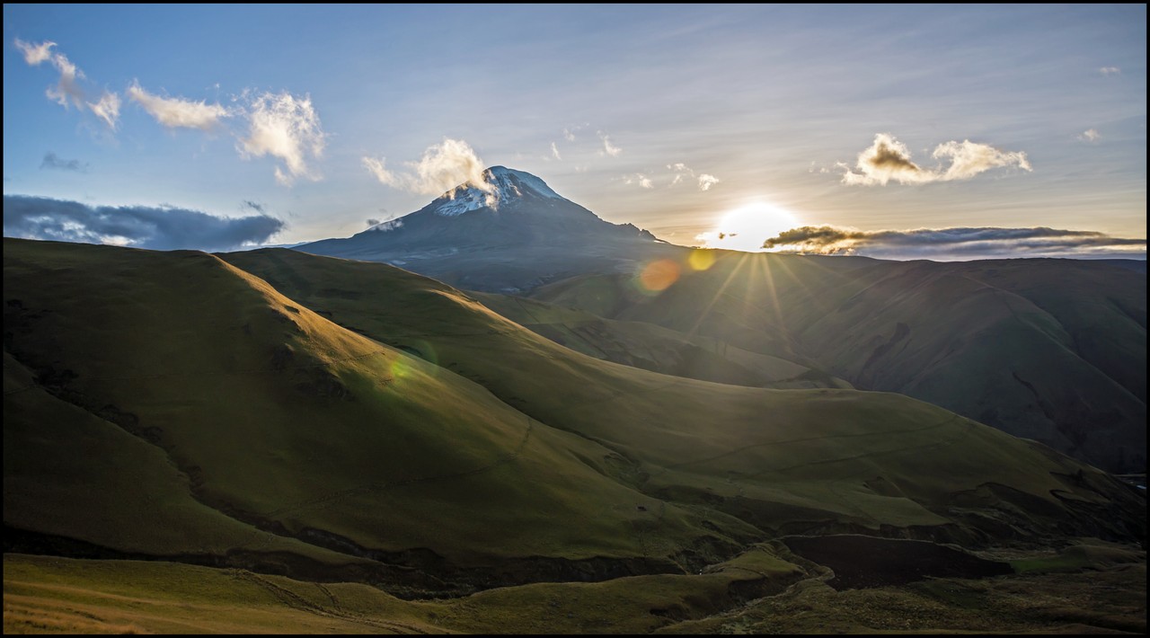 Volcán nevado ecuatoriano con rayos de sol al atardecer