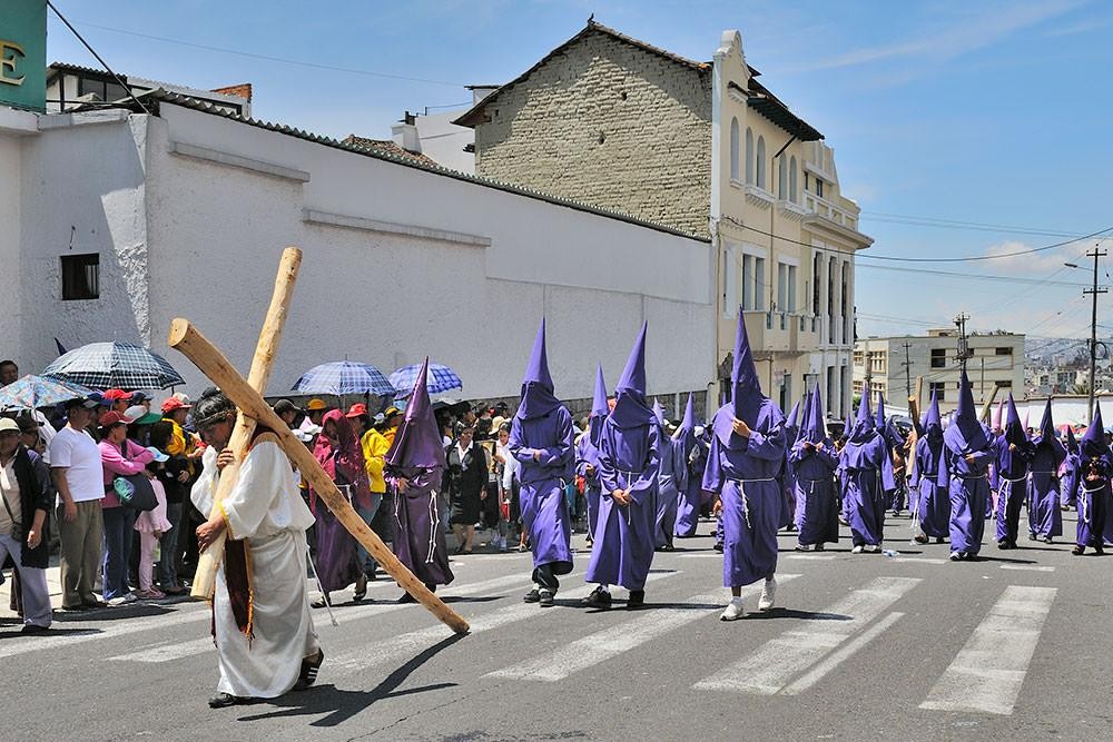 Procesión religiosa tradicional en Ecuador con penitentes de túnicas moradas