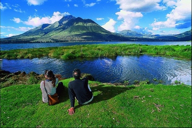 Turistas observan volcán ecuatoriano junto a lago de aguas azules