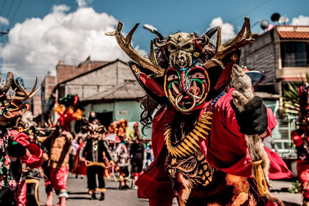 Desfile de festividad tradicional ecuatoriana con personaje demonológico andino