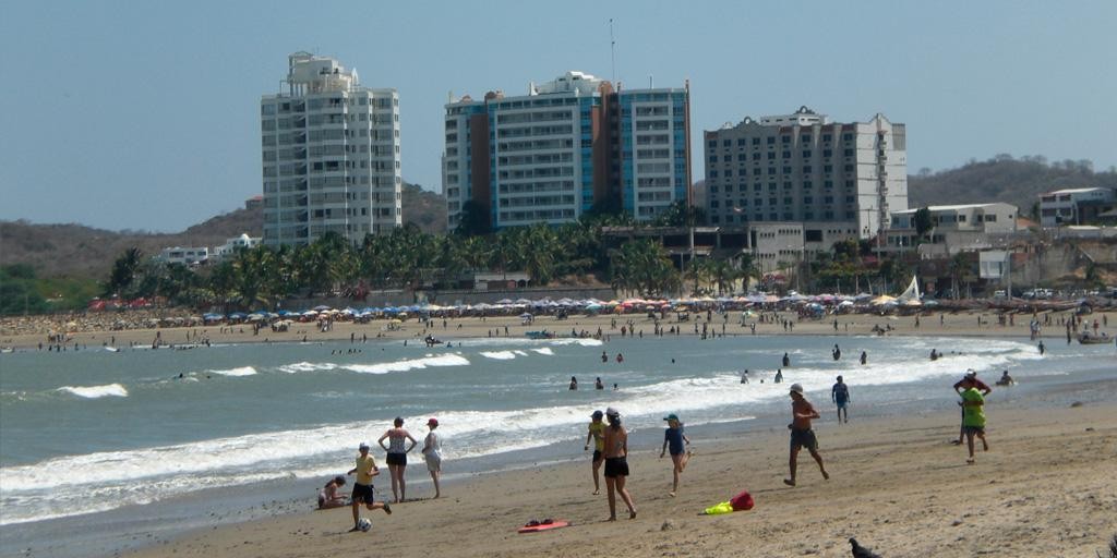 Playa ecuatoriana con bañistas y edificios costeros