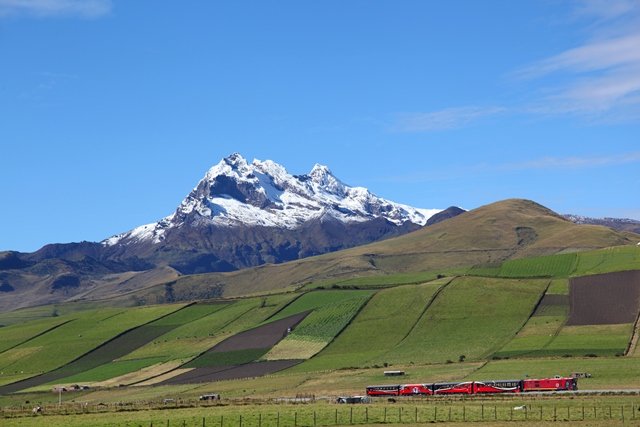 Volcán nevado en la sierra ecuatoriana con ferrocarril y campos cultivados
