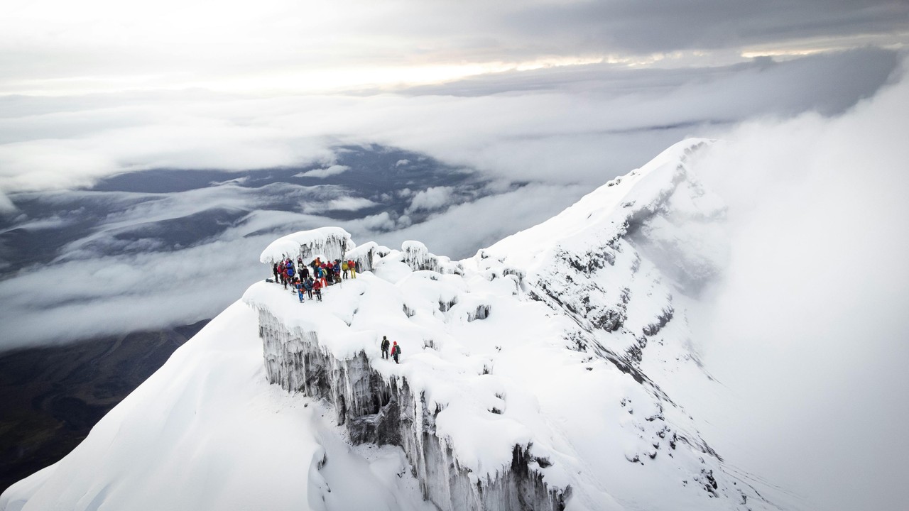 Escaladores en la cumbre nevada del volcán Cotopaxi entre nubes