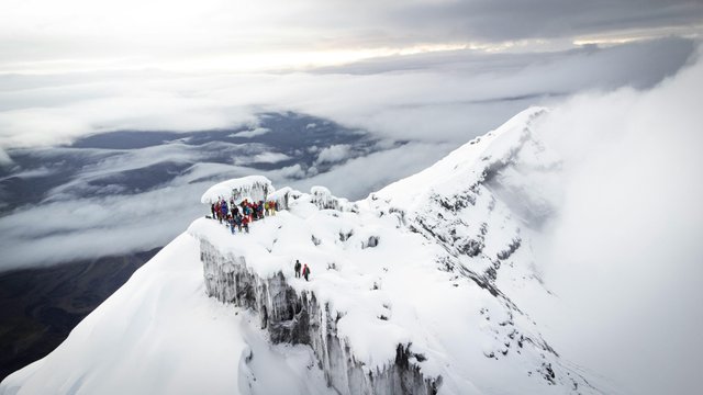 Escaladores en la cumbre nevada del volcán Cotopaxi entre nubes