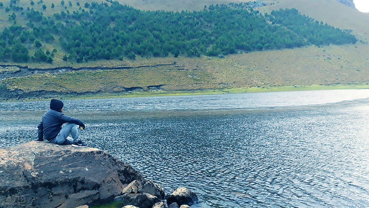 Hombre contemplando lago en paisaje montañoso ecuatoriano